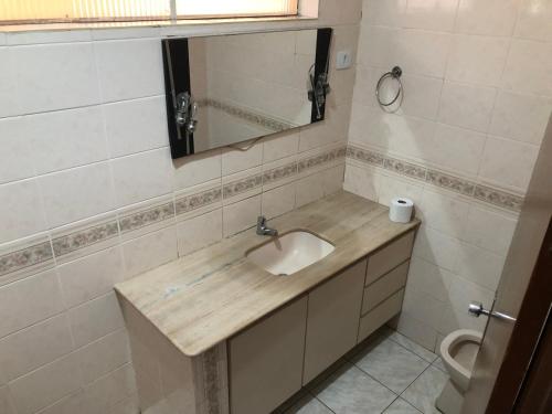 La salle de bains est pourvue d'un lavabo, d'un miroir et de toilettes. dans l'établissement Hostel Vo Mariana, à Goiânia