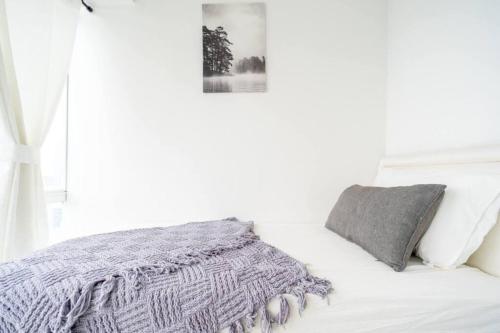a white bedroom with a bed with a gray blanket at Comfy Casa in Jakarta