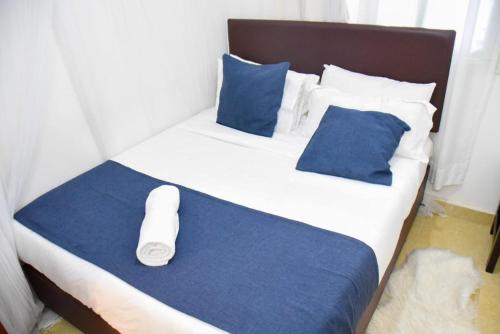 a large white bed with blue sheets and blue pillows at Pacho by Jay in Kisumu