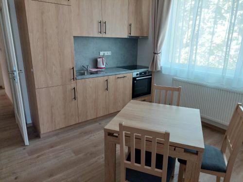 eine Küche mit Holzschränken, einem Tisch, einem Tisch und Stühlen in der Unterkunft Penzion ČESKÁ FARMA in Vysoké Mýto