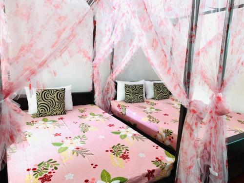 two beds in a room with pink mosquito nets at Peacock Villa Resort in Udawalawe