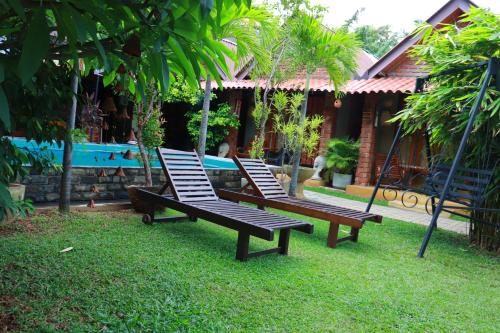 two lounge chairs sitting in the grass near a pool at Negombo The Nature Villa and Cabanas in Negombo
