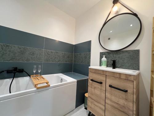 une salle de bain avec une baignoire, un lavabo et un miroir dans l'établissement L'Ancillon Metz Gare Wifi Un-Séjour-à-Part, à Metz