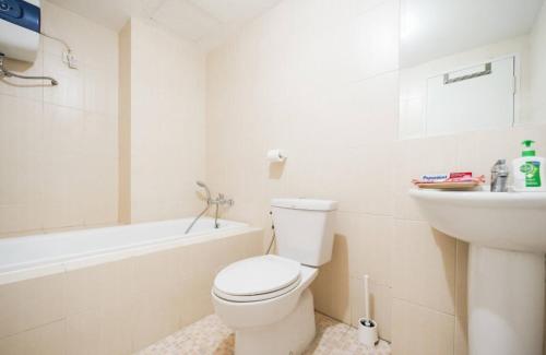a white bathroom with a toilet and a sink at Comfy Casa in Jakarta