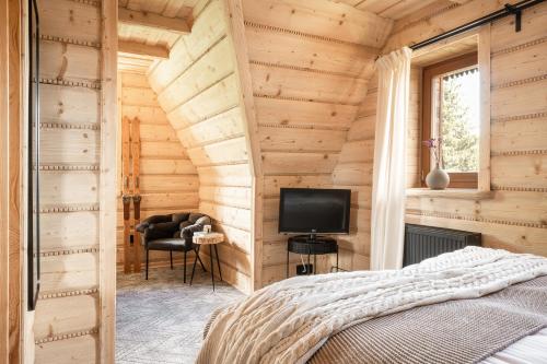 a bedroom with wooden walls with a bed and a television at Dom Górski 878 mnpm in Zakopane