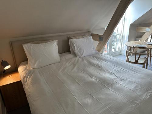Bett mit weißer Bettwäsche und Kissen in einem Zimmer in der Unterkunft Luxe Loft in Historisch Pand in Walstraat Deventer in Deventer