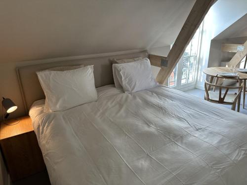 a bed with white sheets and pillows in a room at Luxe Loft in Historisch Pand in Walstraat Deventer in Deventer