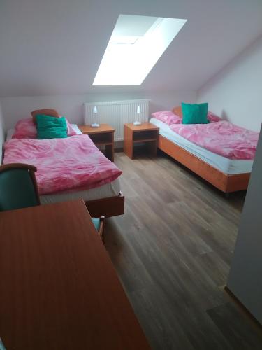 two beds in a room with wooden floors and a window at Penzion Na Protivínské in Strakonice