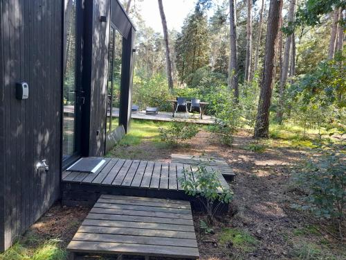 a house with a wooden porch with a bench in the woods at Black Box in Lille