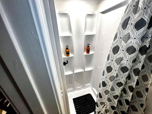 a bathroom with a refrigerator with two bottles on shelves at Tiny House Hideaway with King Bed in Cape Charles