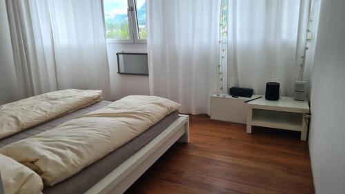 2 Betten in einem Zimmer mit weißen Vorhängen und einem Fenster in der Unterkunft Vesmira_1 in Chur