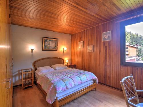 une chambre avec un lit avec des murs en bois et une fenêtre dans l'établissement Appartement cosy 2 pièces proche du centre, avec balcon et casier ski - FR-1-524-58, à Morzine