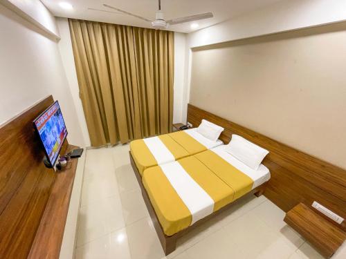 a bedroom with a bed and a flat screen tv at Hari Om Residency in Bhuj