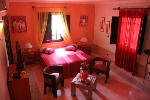 a bedroom with a bed and a table with chairs at VILLA CATHERINE MARRAKECH in Marrakech