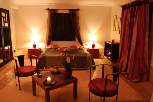 a bedroom with a bed with two chairs and a table at VILLA CATHERINE MARRAKECH in Marrakech