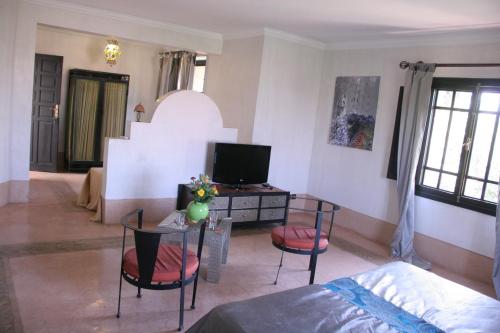 a living room with a television and a desk with chairs at VILLA CATHERINE MARRAKECH in Marrakech