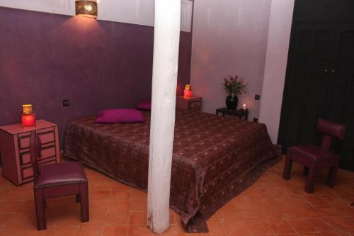 a bedroom with a bed and two chairs and a column at VILLA CATHERINE MARRAKECH in Marrakech