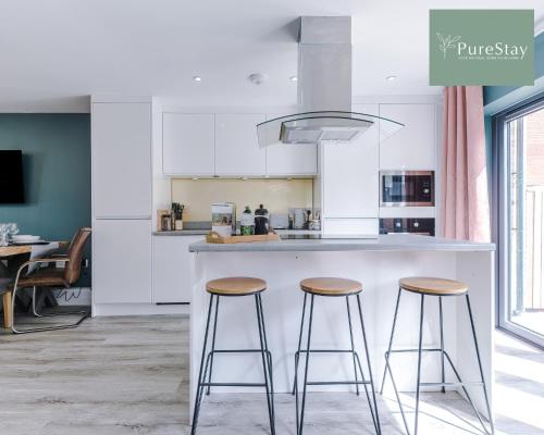 a kitchen with a counter and two stools at Stylish Five Bedroom House By PureStay Short Lets & Serviced Accommodation Failsworth With Free Parking in Manchester