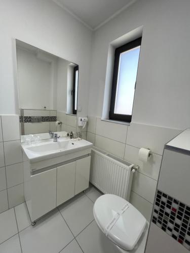 a white bathroom with a toilet and a sink at ALPIN rooms in Topliţa