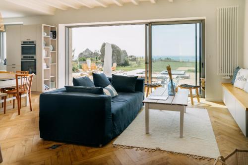 - un salon avec un canapé bleu et une table dans l'établissement LA VILLA COTTON - Superbe Villa avec Spa Face à la mer, à Plobannalec-Lesconil