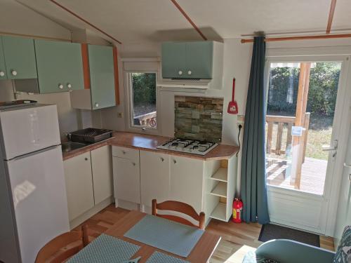 a small kitchen with green cabinets and a table at Mobil Home 4 pers proche Puy du Fou et Montaigu (Vendée 85) in La Boissière-de-Montaigu