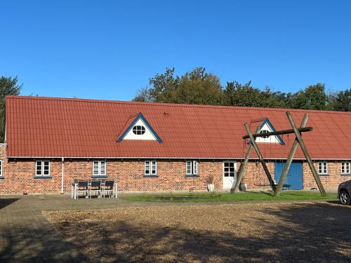 un grand bâtiment en briques avec un toit rouge dans l'établissement Smedegaard værelser, à Skjern