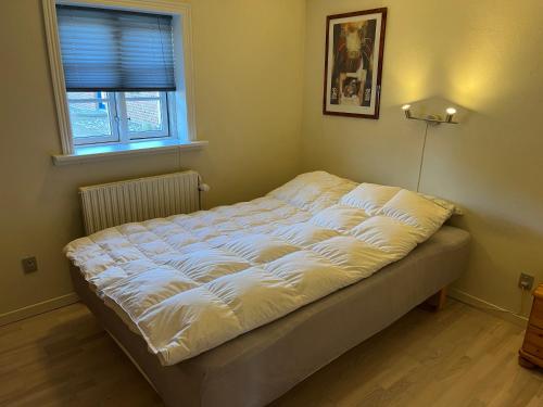 a white bed in a room with a window at Smedegaard værelser in Skjern