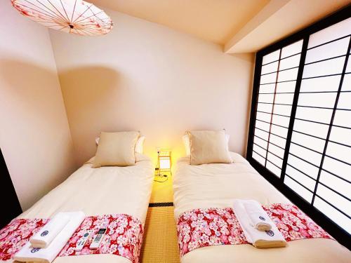 2 camas en una habitación con 2 ventanas en 天王寺駅から徒歩7分, en Osaka