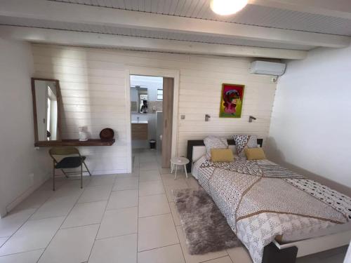 1 dormitorio con cama, mesa y espejo en Villa Sissy: T2 avec jaccuzzi, en Sainte-Anne