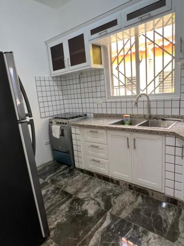 La cuisine est équipée de placards blancs et d'un réfrigérateur noir. dans l'établissement City suite Apartment 1 Cabrera, à Cabrera