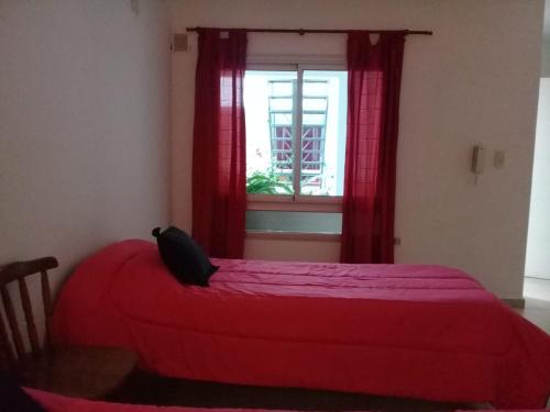 a red bed in a room with a window at Departamento monoambiente centro pb nuevo sencillo Av Belgrano D3 in Marcos Juárez
