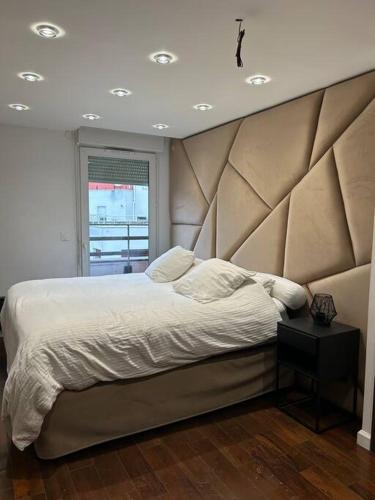um quarto com uma cama grande e uma grande cabeceira. em Logement proche Stade de France em Saint-Denis