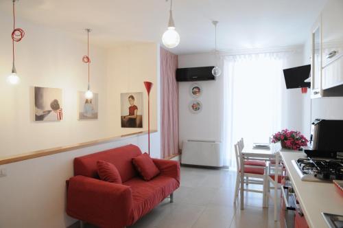 a living room with a red couch and a kitchen at Ypsilhome in Castelbuono