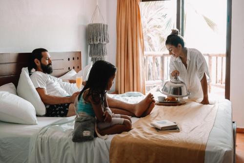 a girl sitting on a bed with a man and a woman at Hotel Rio Lagartos in Río Lagartos