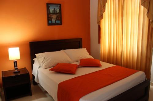 ein Schlafzimmer mit einem Bett mit zwei roten Kissen darauf in der Unterkunft Hotel Arcadia Colonial in Popayan