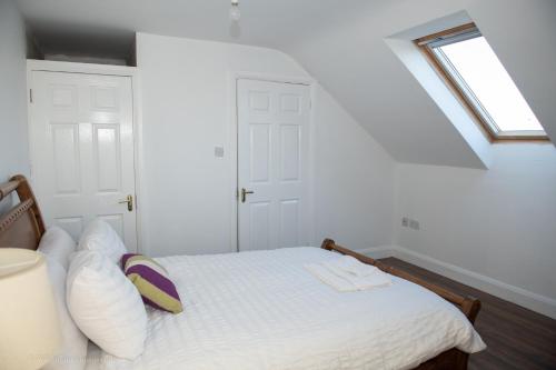 1 dormitorio con 1 cama con sábanas blancas y ventana en Humberts Lodge, 