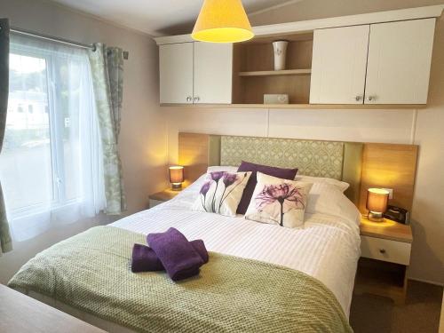 a bedroom with a large bed with purple towels on it at Pottsville Cabin - 2 bed - near Praa Sands Beach in Praa Sands