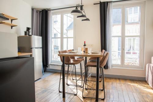 布魯瓦的住宿－Le Petit Nicolas - Centre historique de Blois - NETFLIX, JEUX, RETROJECTEUR，厨房配有桌椅和冰箱。