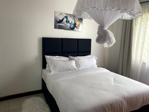a bedroom with a large bed with white sheets at Pacho- All en-suite 2br in Kisumu