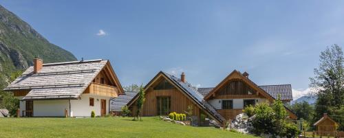 a house with a slate roof with mountains in the background at PRIVILLAGE Stare - Villa & Chalet in Bohinj
