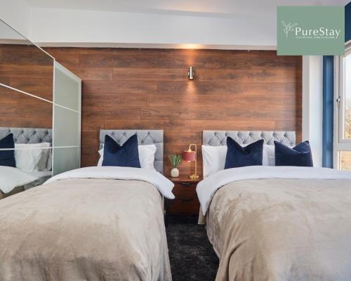 1 dormitorio con 2 camas y almohadas azules y blancas en Three Bedroom House By PureStay Short Lets & Serviced Accommodation Manchester With Free Parking, en Mánchester