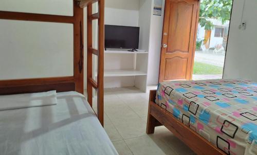 a bedroom with a bed and a flat screen tv at Palmendros Hosteria in Montañita