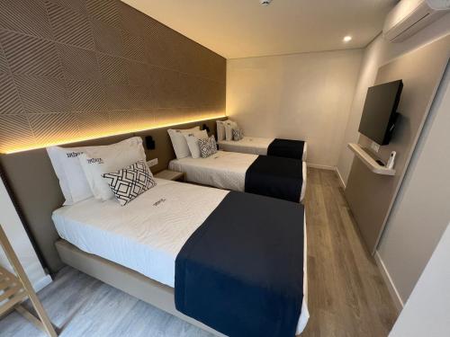 a small room with two beds and a flat screen tv at Patria Hotel in Lisbon