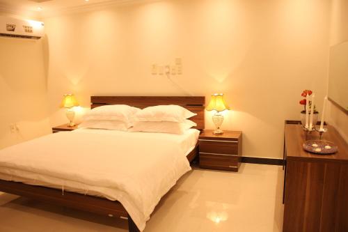 a bedroom with a large bed and two night stands at الجناح الأبيض للأجنحه الفندقية in Dammam