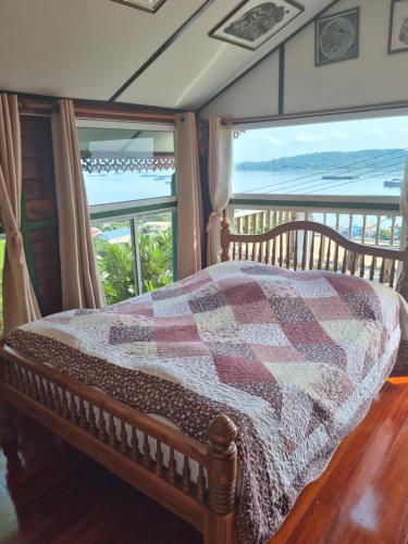 a bedroom with a bed with views of the ocean at บ้านนางฟ้า เกาะสีชัง Baan Nangfa in Ban Tha Thewawong