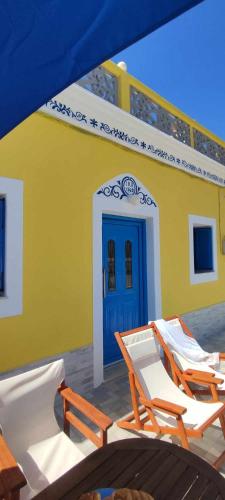 a yellow building with chairs and a blue door at Olympos Princess in Olympos