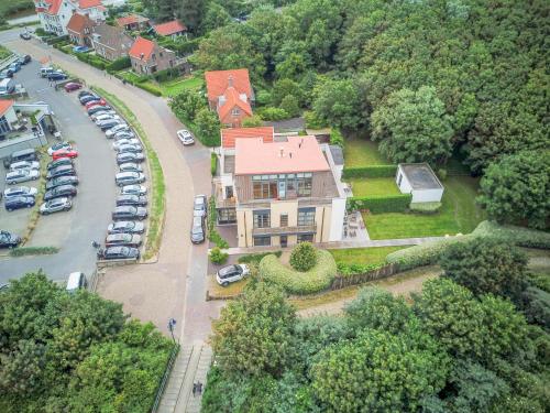 a large house with cars parked in a parking lot at Maanvis in Cadzand-Bad