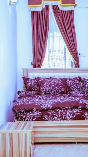 a bedroom with a bed with red curtains and a window at Select Winsome 1 Room, 1 King-sized Bed in Abuja