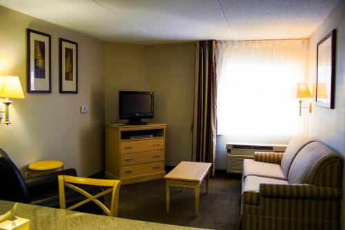 a living room with a couch and a tv in a hotel room at Candlewood Suites Wilson by IHG in Wilson