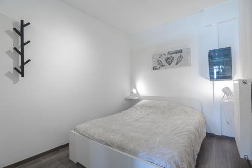 un pequeño dormitorio blanco con una cama. en Les Figuiers - Appartement Cozy avec Jardin, en Andenne